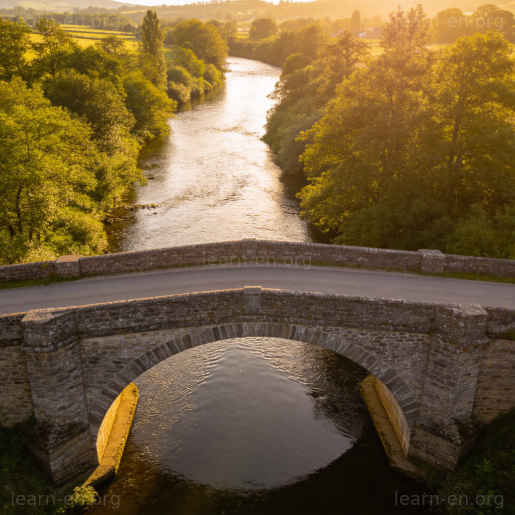Stone arch bridge spanning a river in rural landscape